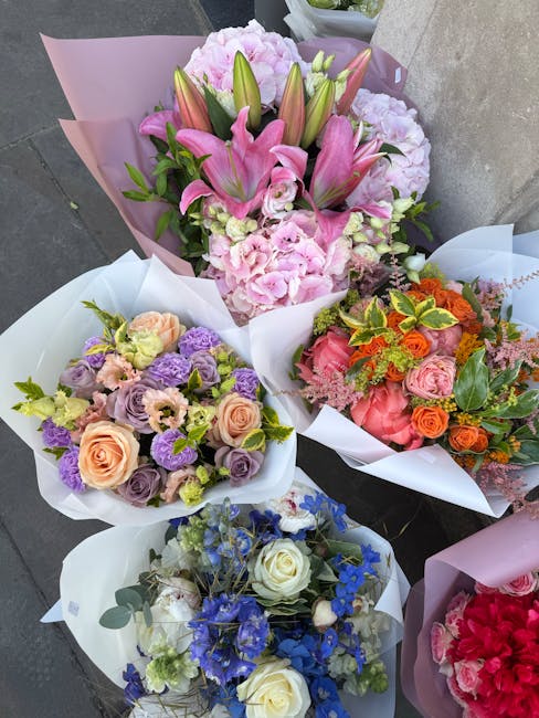 A collection of five floral arrangements featuring a variety of fresh flowers. The top bouquet showcases pink lilies, light pink hydrangeas, and creamy roses wrapped in pink and purple tissue paper. T